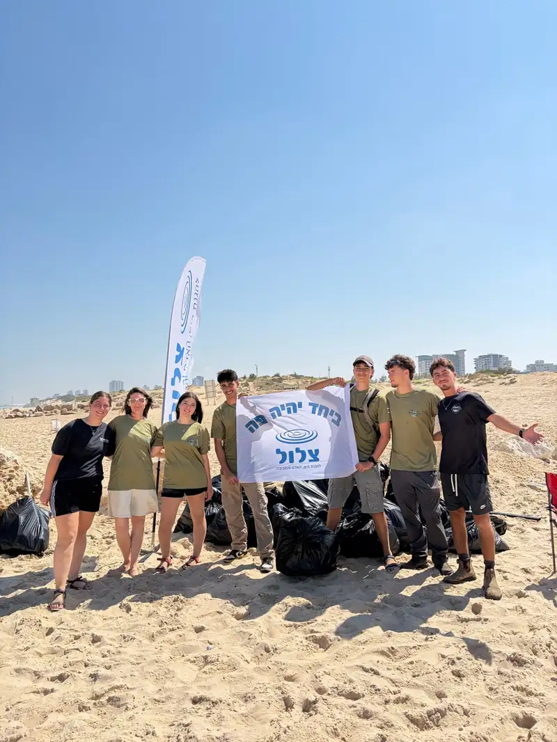 מתנדבים בחוף באר טוביה עם דגל עמותת צלול